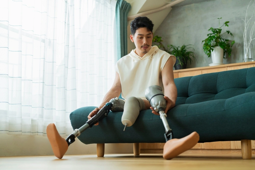 Disabled man with amputated leg sitting on couch